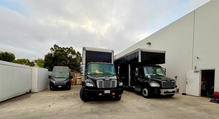 The Elite Movers fleet: two Freightliner moving trucks and a Ram ProMaster van