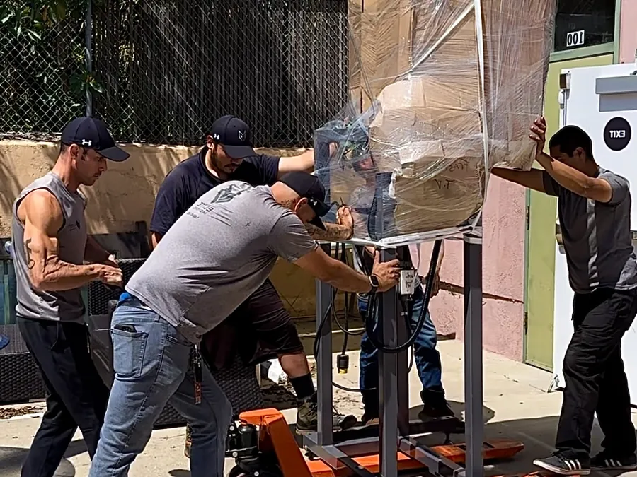 Lifting a shrink-wrapped machine onto a dolly