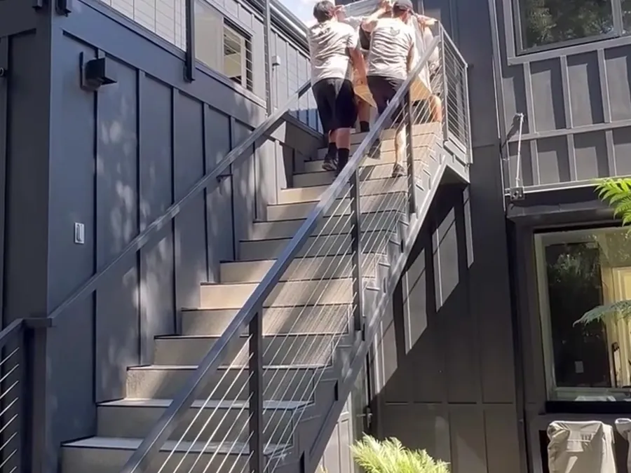 Elite crew carrying furniture up an exterior staircase